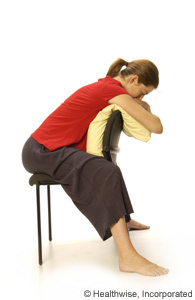 A woman sitting backwards in a chair and leaning on a pillow